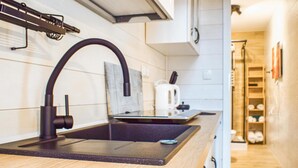 Una cocina con un grifo negro, encimera de madera y hervidor blanco.