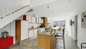 A modern kitchen with a central island, a red cabinet, and a staircase. - 2 bedroom cozy home in Rømø (Rømø)