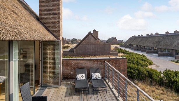 A modern building with a glass facade, a brick chimney, and a thatched roof. - 2 bedroom cozy home in Rømø (Rømø)