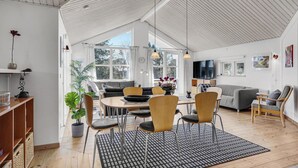A modern living space with a dining area, a sofa, and a TV.