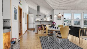 A modern kitchen with a dining area, wooden flooring, and large windows.