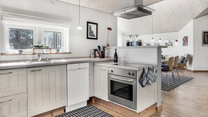 A modern kitchen with white cabinetry, a built-in oven, and a large window providing natural light.