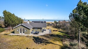 A single-story house with a patio, a view of the beach, and a clear sky.