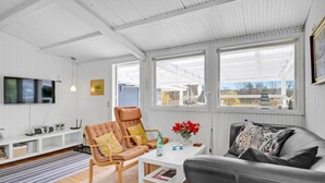 Un salon moderne comprenant un téléviseur, un canapé, un fauteuil et une table basse.