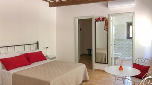 Une chambre à coucher avec un lit, une table de chevet et une petite table ronde accompagnée d’une chaise.