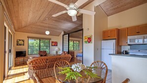 A spacious living area with a glass dining table, wicker furniture, and a ceiling fan. - 180' view 🌊& Mountain View! 1000 feet to 🏝watch 🌅 (Koloa)