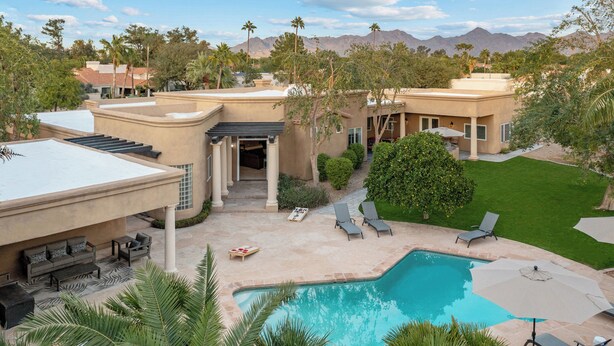 A pool area with lounge chairs, a pergola, and a view of a mountain range. - The Big Dog – Private Custom Estate – Heated Pool & Spa – Game Room (SCOTTSDALE)