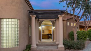 A building entrance with a covered porch, a glass door, and a view into a room with a sofa and a table. - The Big Dog – Private Custom Estate – Heated Pool & Spa – Game Room (SCOTTSDALE)