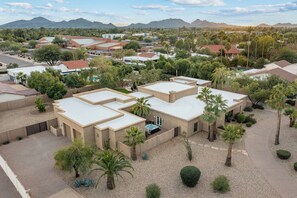 A residential area with multiple houses, a paved courtyard, and palm trees. - The Big Dog – Private Custom Estate – Heated Pool & Spa – Game Room (SCOTTSDALE)
