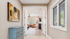 A hallway with a blue dresser, a painting, and a dining area with chairs and a table. - The Big Dog – Private Custom Estate – Heated Pool & Spa – Game Room (SCOTTSDALE)