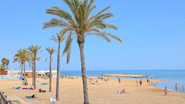 A beach with palm trees, people sunbathing, and a clear blue sky. - Stunning home in Marina di Modica with WiFi (Marina di Modica)