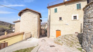 A narrow stone pathway leading to a traditional stone building with a small entrance and a wooden door. - 2 bedroom awesome home in Preci (Preci)