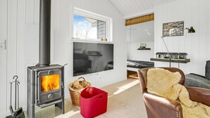 A cozy living room with a wood-burning stove, a television, and a comfortable chair. - Beautiful home in Juelsminde with WiFi (Horsens)