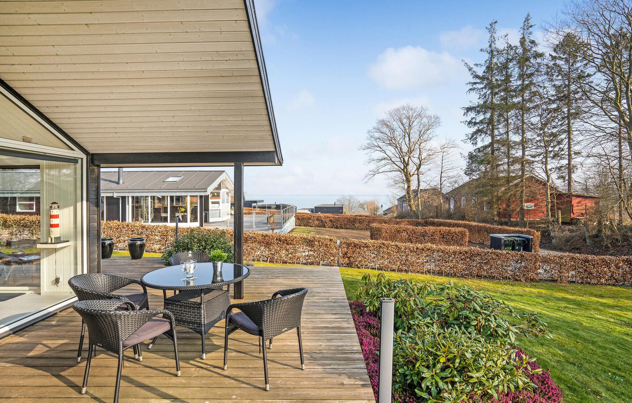 Een modern huis met een terras, zitplaatsen buiten en uitzicht op zee.