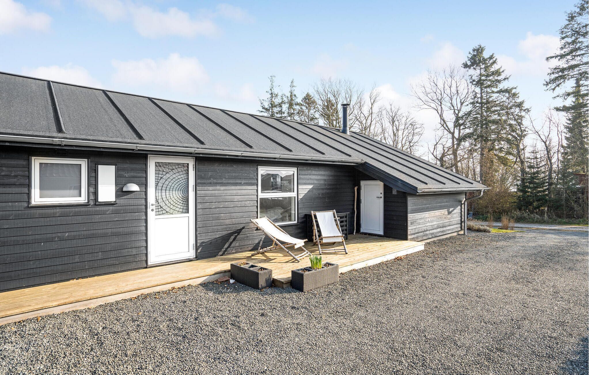 A modern building with a dark exterior, a sloped roof, and a gravel driveway.