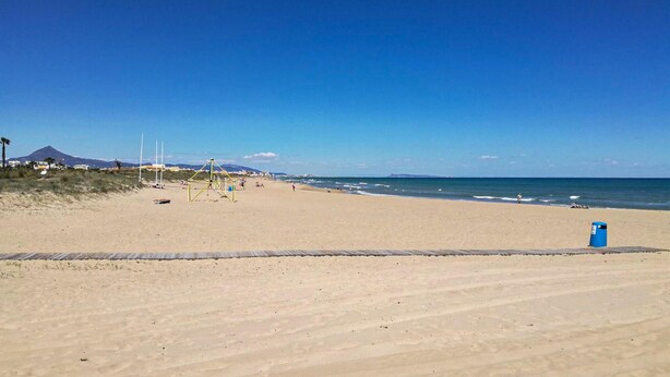 A wide sandy beach with a clear blue sky, a few people, and a distant mountain. - Beautiful home in La Font den Carros (La Font den Carros)