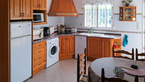 A compact kitchen with wooden cabinets, a washing machine, a microwave, a toaster, and a sink. - Beautiful home in La Font den Carros (La Font den Carros)