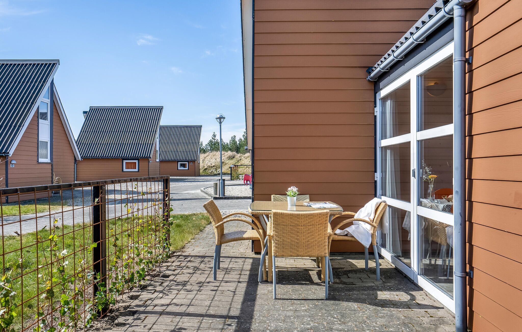 Eine Terrasse mit Korbmöbeln, einer Glastür und Blick auf angrenzende Häuser.