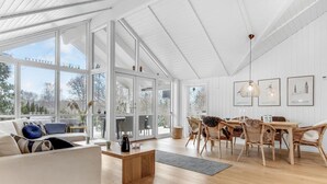 A spacious room with large windows, a dining area with wicker chairs, and a coffee table. - Lovely home in Hornbæk with WiFi (Hornbæk)