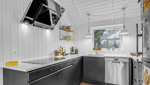 A modern kitchen with a large island, stainless steel appliances, and a window providing natural light. - Lovely home in Hornbæk with WiFi (Hornbæk)