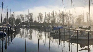 A marina with boats docked, calm water, and bare trees in the background. - Cozy home in Makkum with kitchen (Makkum)