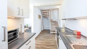 A modern kitchen with a built-in oven, a wooden staircase, and a compact layout. - Nice home in Süssau/Ostsee with sauna (Süssau/Ostsee)
