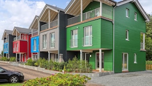 A row of colorful townhouses with balconies, a gravel driveway, and a car parked in front. - Nice home in Süssau/Ostsee with sauna (Süssau/Ostsee)