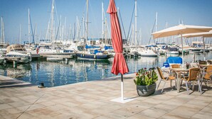 Marina con barcos amarrados, asientos exteriores y cielo despejado.