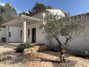 A modern house with a covered porch, a stone wall, and an olive tree. - Spacious and quiet villa classified 4 * furnished with tourism (Flassans-sur-Issole)