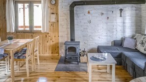Ein gemütliches Zimmer mit Holzboden, einer Couch, einem Esstisch mit Stühlen und einem Kamin.