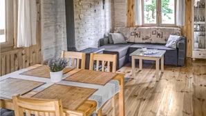 Ein gemütliches Wohnzimmer mit Holzboden, einer Couch, einem Esstisch mit Stühlen und einer Topfpflanze.