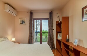 Relax in this inviting space with a large bed, nightstand, and window offering a view of lush greenery.