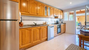 Eine Küche mit Holzausstattung, Edelstahlgeräten und einer gefliesten Spritzschutzwand.