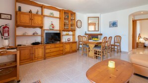Ein Wohnzimmer mit Holzmöbeln, einem Fernseher und einem Essbereich mit Stühlen und einem Tisch.