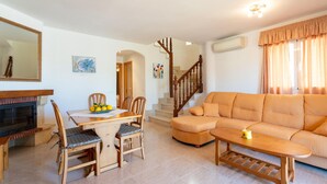 Ein Wohnzimmer mit einer Couch, einem Esstisch, Stühlen und einem Kamin.