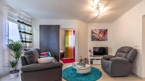 A modern living room with a grey sofa, a teal rug, a TV, and a painting on the wall. - 2 bedroom beautiful apartment in Liznjan (Liznjan)