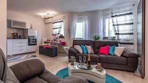 A modern living room with a brown sofa, a white coffee table, and a dining area with a white table and chairs. - 2 bedroom beautiful apartment in Liznjan (Liznjan)