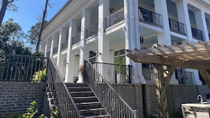 Un immeuble à plusieurs étages, doté de colonnes blanches, de balcons et d’un escalier menant à l’entrée.
