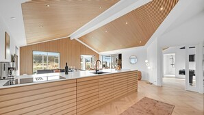 Une cuisine moderne avec un plafond en bois, de grandes fenêtres et un îlot central.