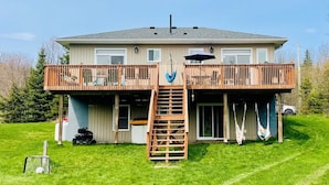 Ein zweistöckiges Haus mit Balkon, einer Leiter, die zu der oberen Etage führt, und einem Schaukelstuhl.