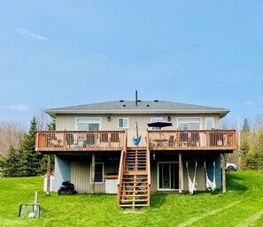 Ein zweistöckiges Haus mit Balkon, einer Leiter, die zu der oberen Etage führt, und einem Schaukelstuhl.