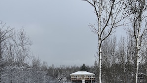 Schneebedeckte Landschaft mit einem zweistöckigen Gebäude, das einen Balkon und eine Garage hat.