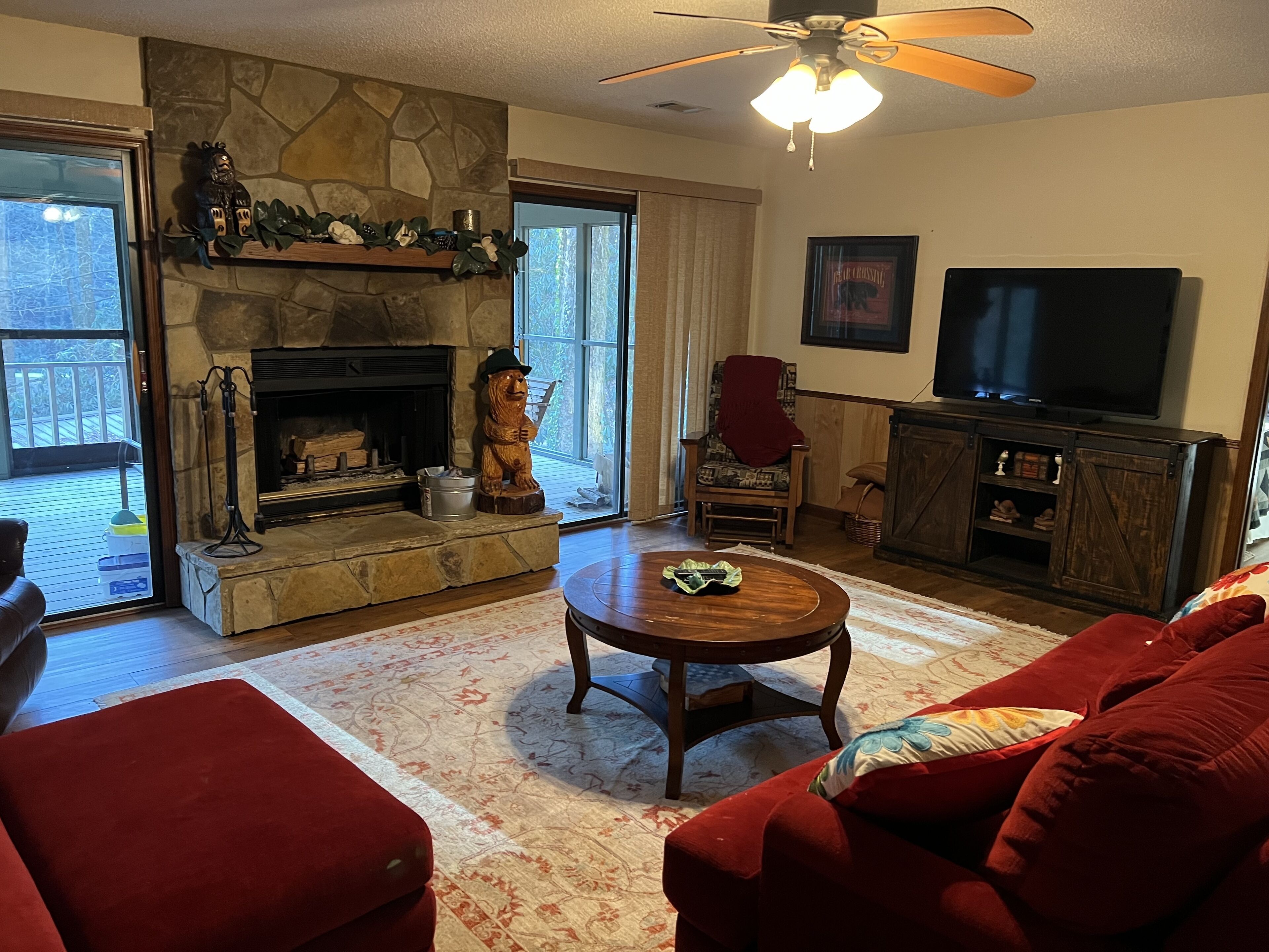 Una sala de estar acogedora con chimenea de piedra, un televisor y un sofá rojo.