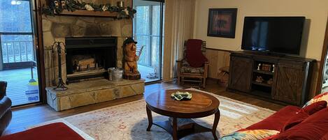 Una sala de estar acogedora con chimenea de piedra, un televisor y un sofá rojo.