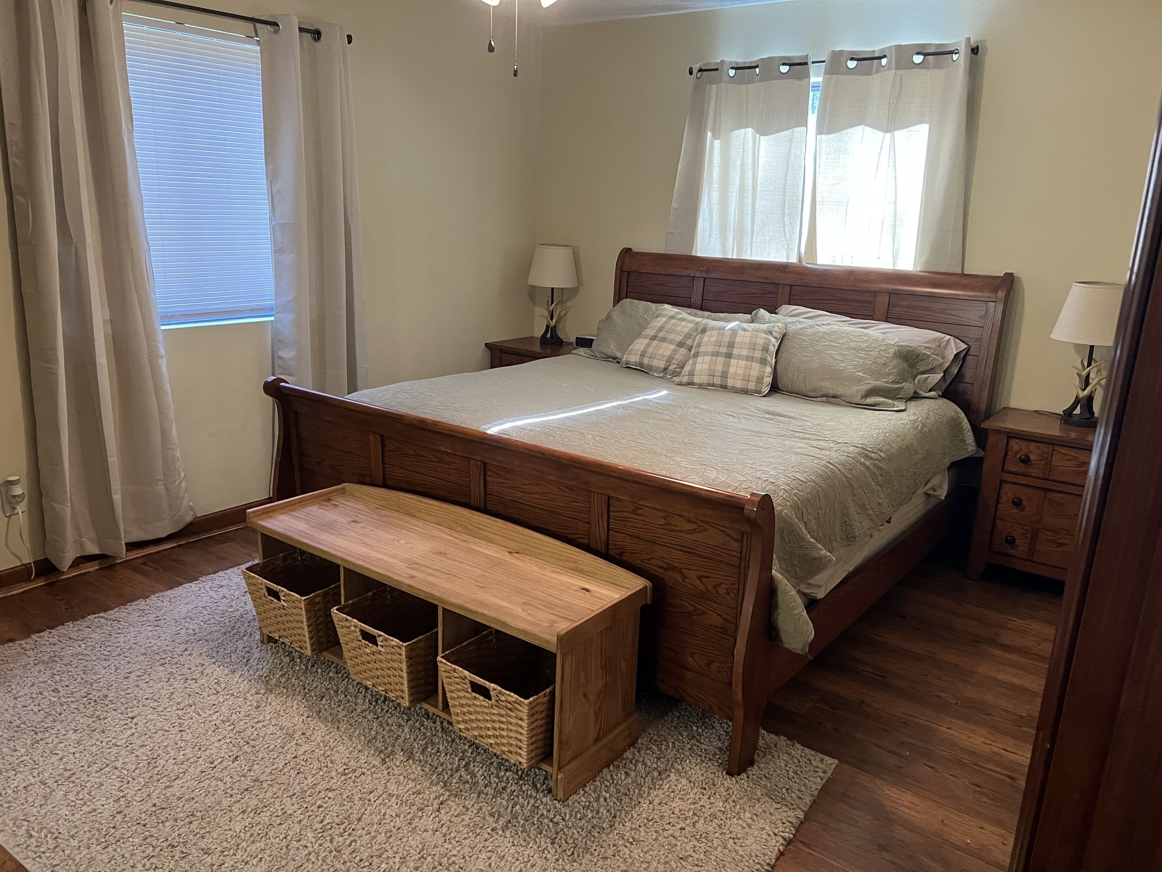 A bedroom with a wooden bed, bedside tables, a bench, and storage baskets.