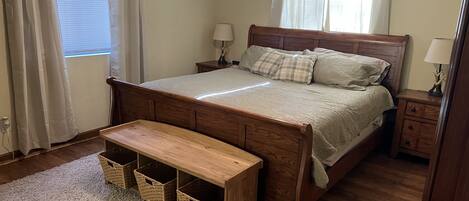 A bedroom with a wooden bed, bedside tables, a bench, and storage baskets.