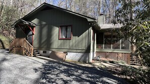 Une cabane avec une véranda, une fenêtre et une cheminée.