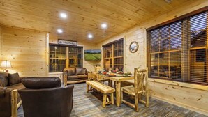 Un interior de madera con una mesa de comedor, sillas, un sofá y una televisión.
