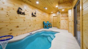 Un interior de madera con piscina, sillas azules y un aro de baloncesto.
