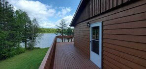Una terraza de madera con vista a un lago y un bosque.
